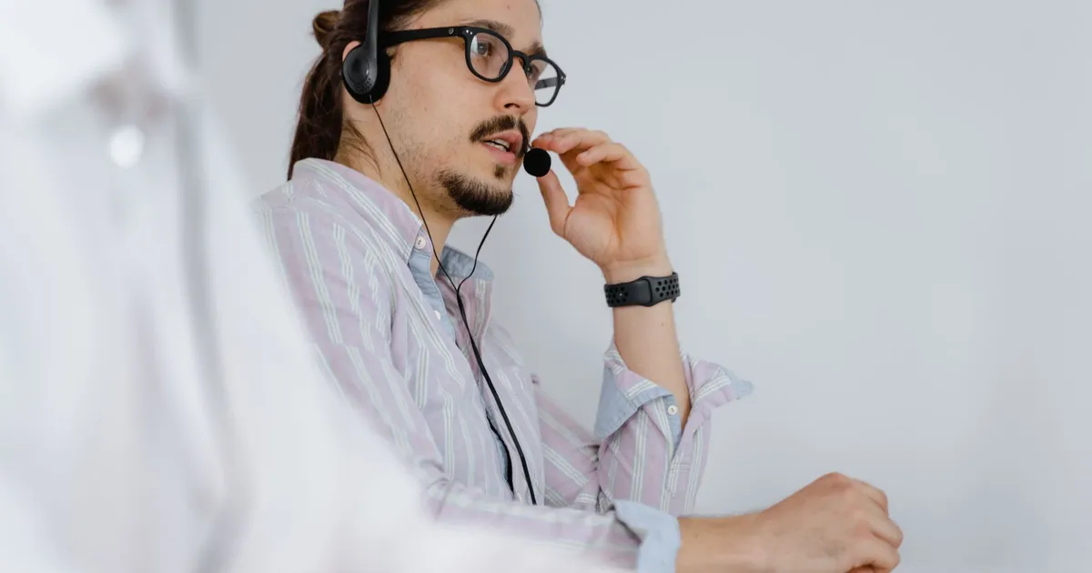Focused customer service agent speaking on a headset in a modern office environment.