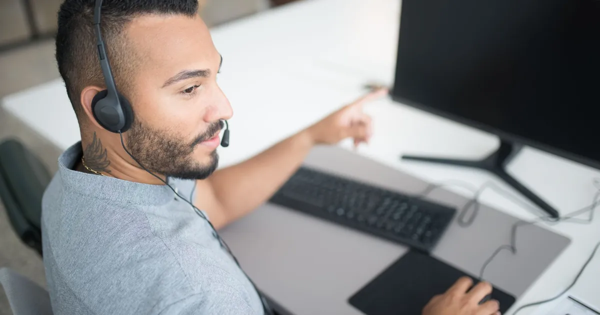 Customer service agent using a computer and headset within a modern office setting.