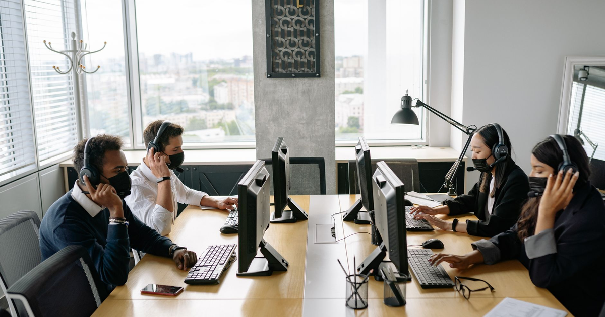 Professional team in a modern call center working collaboratively with headsets and computers.
