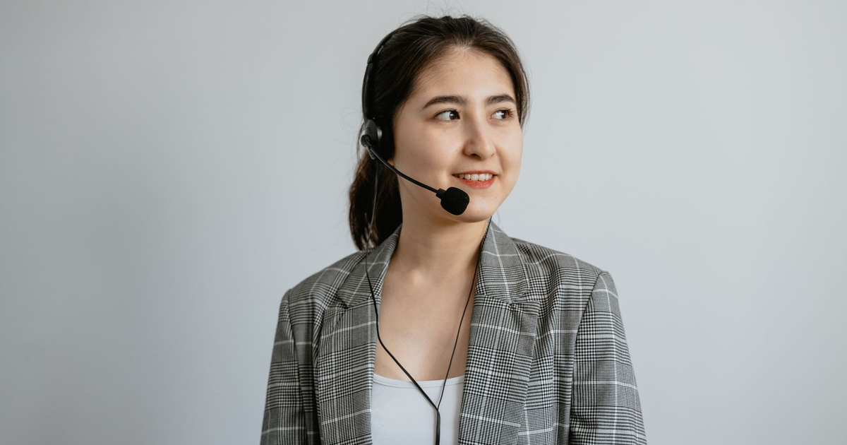 Smiling young woman in a call center wearing a headset ready to assist customers.