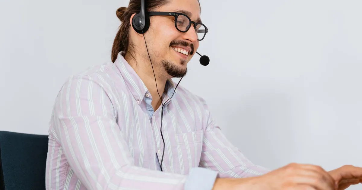 Smiling call center agent wearing headset assisting customers indoors.