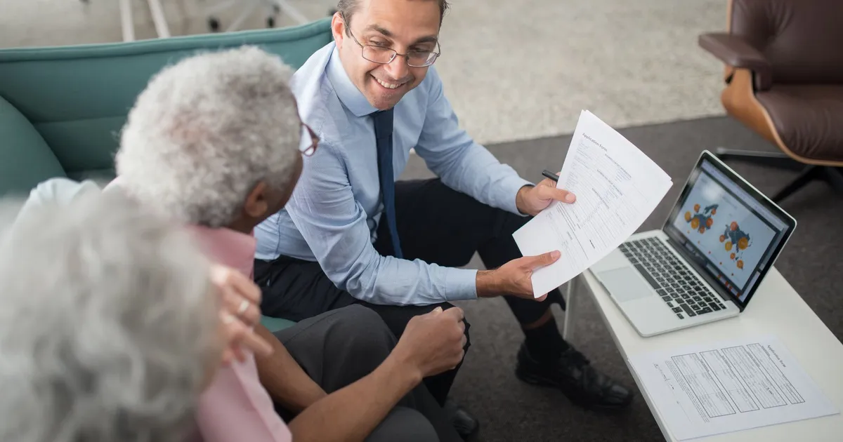 Financial advisor discussing documents with senior clients in an office setting.