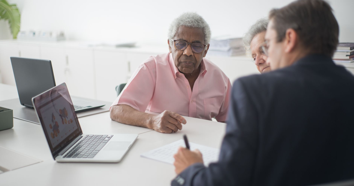 Senior couple discussing insurance options with a consultant in an office setting.