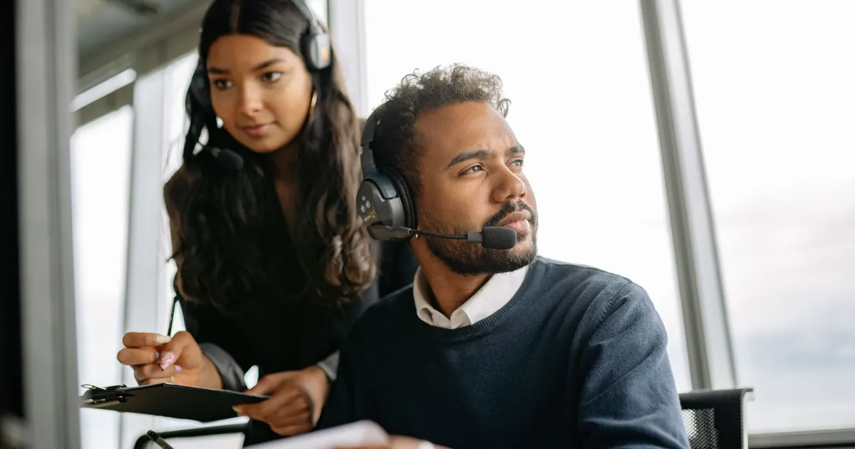 Two professionals working with headsets in a modern office environment, focused on service tasks.