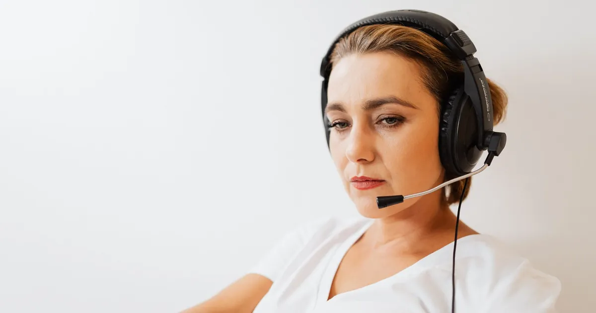 Focused woman wearing a headset working in customer support with a white background.