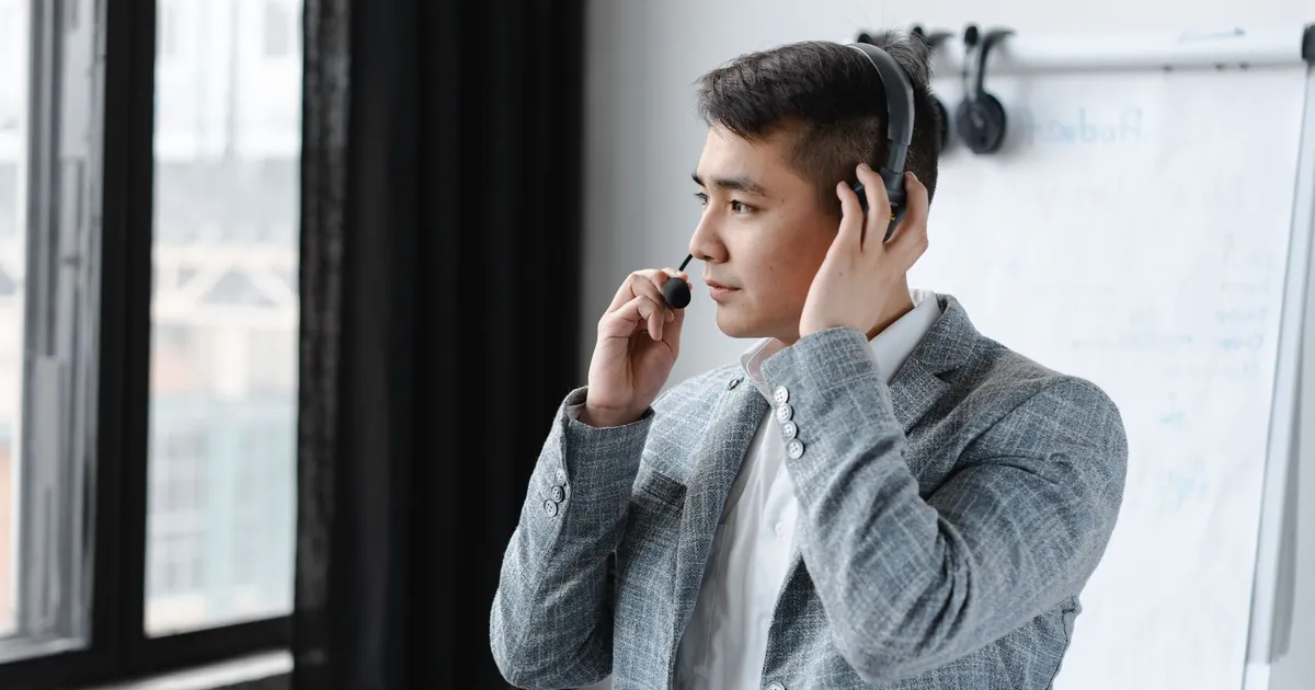 Asian male call center agent wearing a headset during a call in an office setting.
