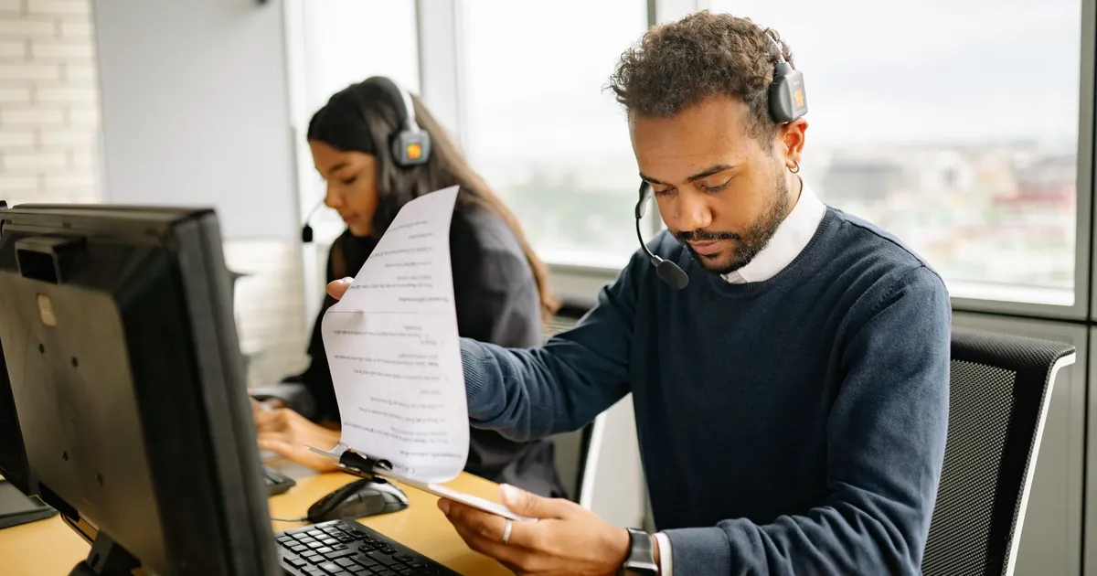 Call center agents with headsets working in a modern office setting, reviewing documents.